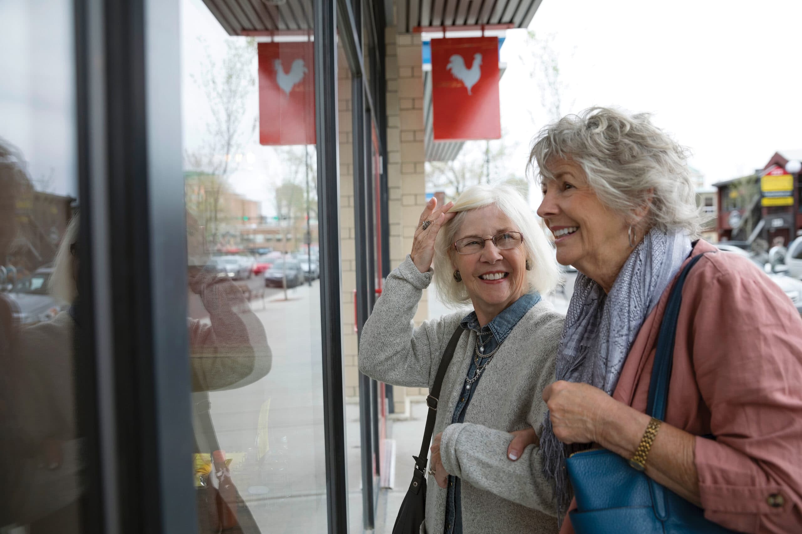 Smiling senior women window shopping at urban storefront